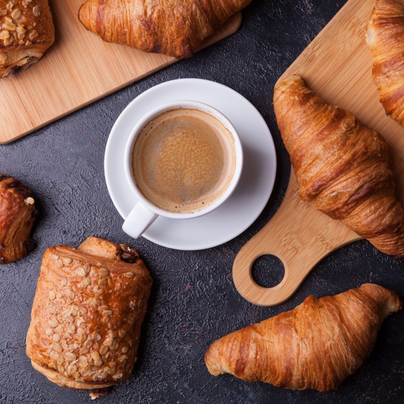 Assortment of pastries with coffee cup on wooden table background. French cuisine.