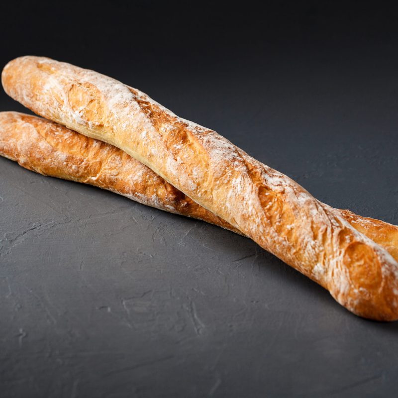 Close-up photo of two french baguettes on gray textural background